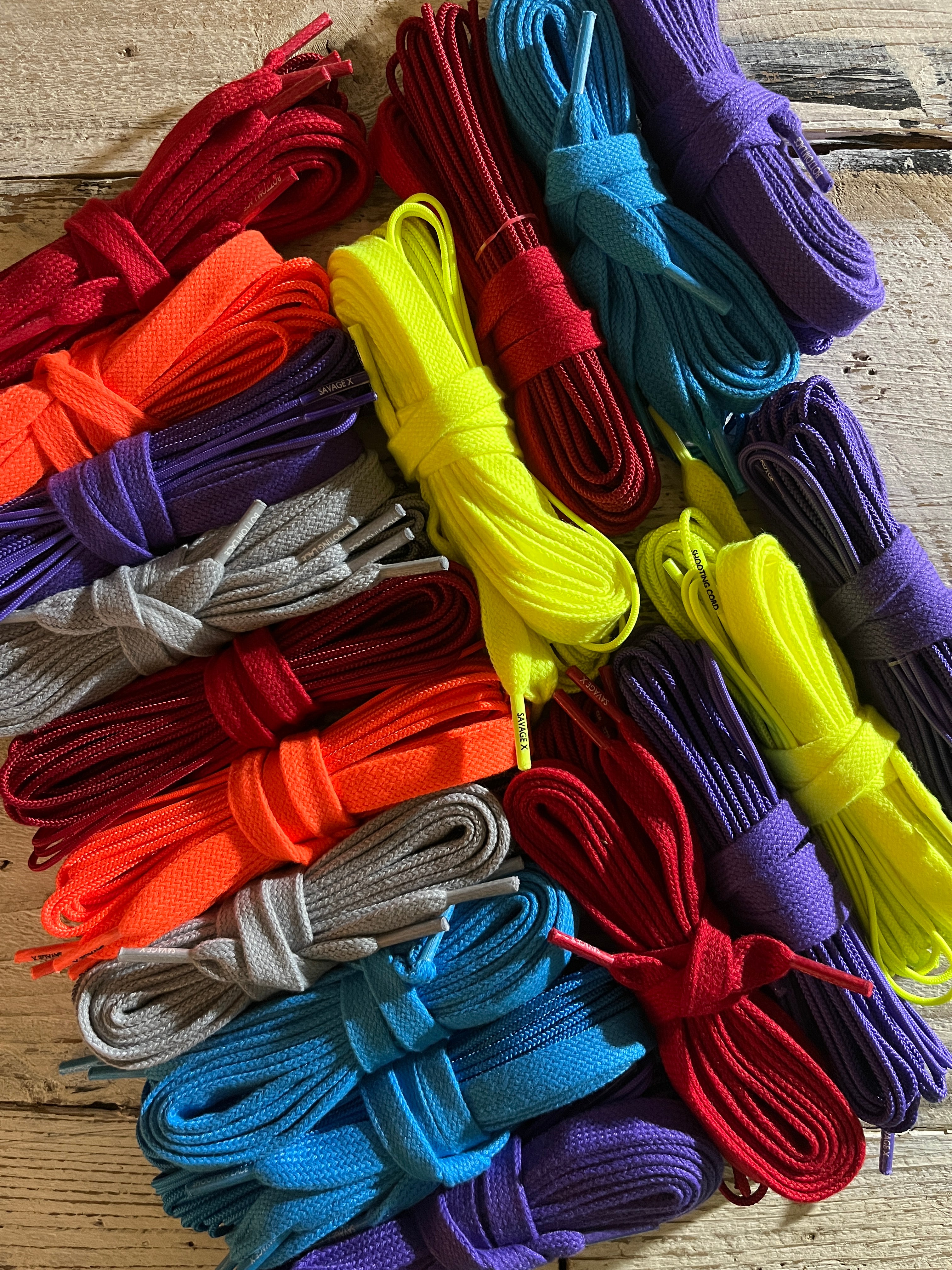 A pile of lacrosse string sets in different colors on a wood table